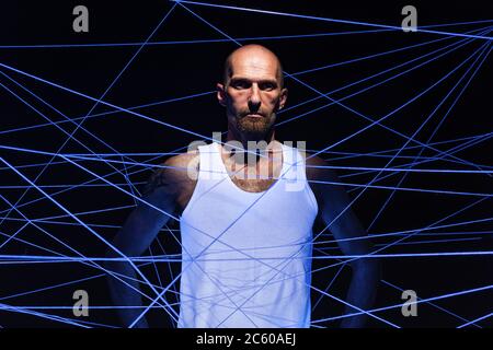 Photo d'un homme adulte emmêlé dans des fils blancs dans des ultraviolets Banque D'Images