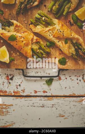 Asperges vertes cuites enveloppées de pâte feuilletée. Servi sur un panneau en bois. Avec espace de copie Banque D'Images