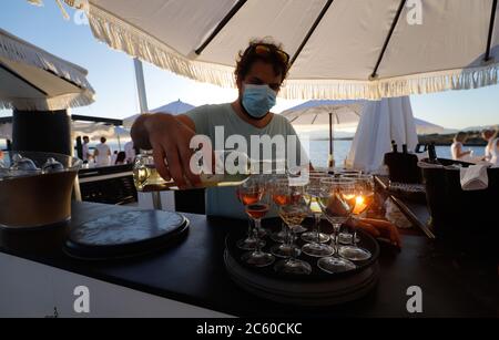 23 juin 2020, Espagne, Palma: Un serveur avec masque sert du vin en verre au Bar Purobeach de Cala Estancia sur la plage Playa de Palma. Photo: Clara Margais/dpa Banque D'Images