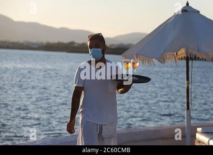 23 juin 2020, Espagne, Palma: Un serveur avec masque facial sert les clients du Bar Purobeach à Cala Estancia sur la plage Playa de Palma. Photo: Clara Margais/dpa Banque D'Images