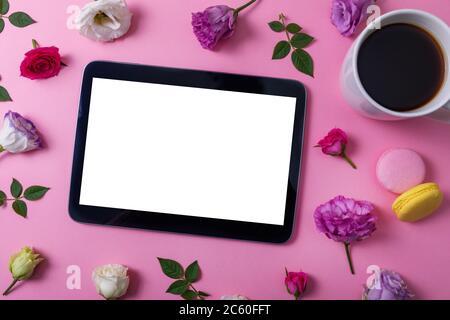 tablette numérique avec écran vierge sur fond rose avec fleurs et tasse à café. vue du dessus Banque D'Images