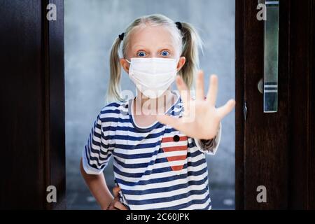 Petit enfant montrant le geste de la main Stop virus. Les enfants portant des masques médicaux sortent pour la promenade à l'extérieur après être restés à la maison en raison de l'activité interdite dans la rue. Banque D'Images