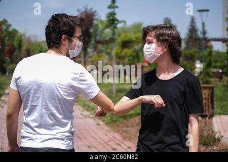 Salutation avec le coude en jours d'épidémie de coronavirus. Nouveau style de salutation pendant l'épidémie de coronavirus. Deux amis se sont cognés les coudes à l'extérieur. Banque D'Images