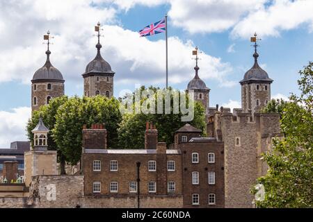 Les quatre tours d'angle de la tour blanche centrale contre le ciel avec le drapeau de l'Union, Tour de Londres Banque D'Images