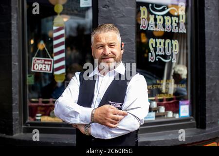 Sean Lawlor copropriétaire de Cambridge Barbershop sur Lisburn Road de Belfast se tient à l'extérieur de son magasin, tandis que les coiffeurs et salons de beauté rouvrent en Irlande du Nord, une partie de la dernière mesure pour atténuer les restrictions du coronavirus. Banque D'Images