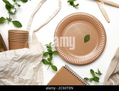 sac textile et vaisselle jetable en papier marron artisanal, feuilles de menthe verte sur fond blanc. Vue de dessus, concept de rejet plastique, zéro Banque D'Images