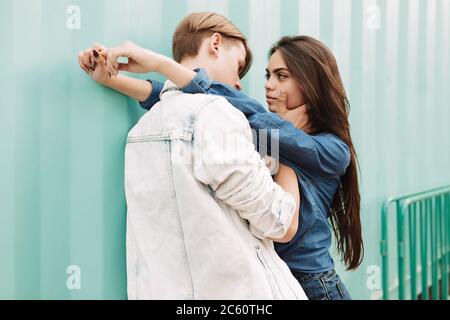 Portrait d'un jeune beau couple s'embrassant tout en se tenant sur fond bleu Banque D'Images