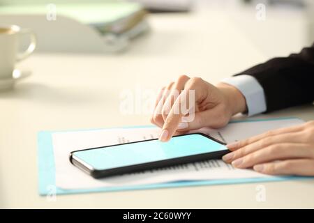 Gros plan de la femme de direction signant le contrat numérique sur un smartphone écran éclairé avec le doigt au bureau Banque D'Images