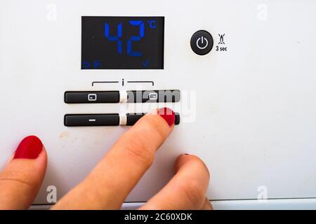 Main femme essayer de désactiver et sur le chauffage central dans la chambre. Les mains sur le panneau de commande de chauffage central. Fille main température de réglage pour Banque D'Images