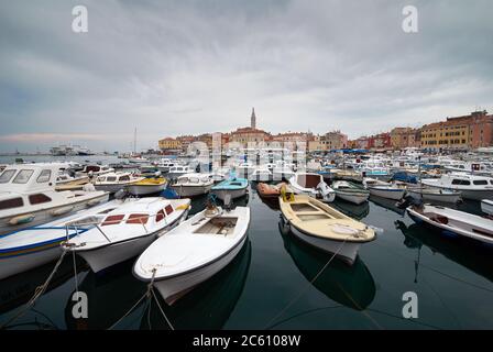 Rovinj, Croatie. Bateaux à moteur et bateaux sur l'eau dans le port de Rovinj. Maisons médiévales anciennes de la vieille ville. Yachts atterrissant, tour avec horloge sur le backgro Banque D'Images