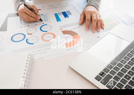 Femme d'affaires analyse le document dans ses mains.graphiques et diagramm sur l'écran de bloc-notes.financier et concept d'investissement. Banque D'Images