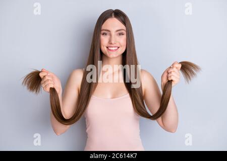 Photo de l'apparence parfaite modèle dame tient les mains long hairdo boucles extrémités bon état nouveau masque effet satisfait usure beige singulet isolé gris Banque D'Images