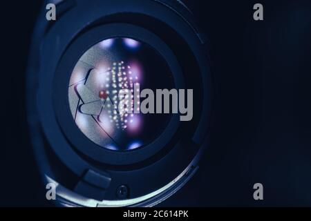 Gros plan sur un magnifique objectif sur fond sombre et lumineux à réflexion rouge. Vue macro. Banque D'Images