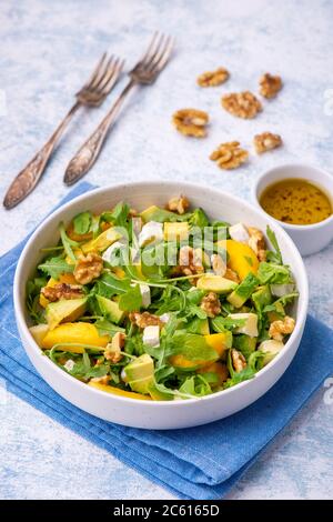 Salade d'arugula aux pêches, avocat, camembert et noix, sur le dos léger. Banque D'Images