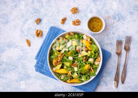 Salade d'arugula aux pêches, avocat, camembert et noix, sur le dos léger. Banque D'Images