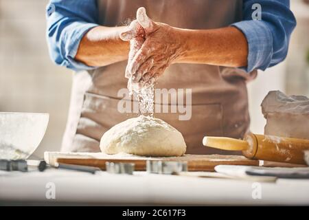 Vue rapprochée du boulanger en cours. Pain maison. Mains préparant la pâte sur une table en bois. Banque D'Images