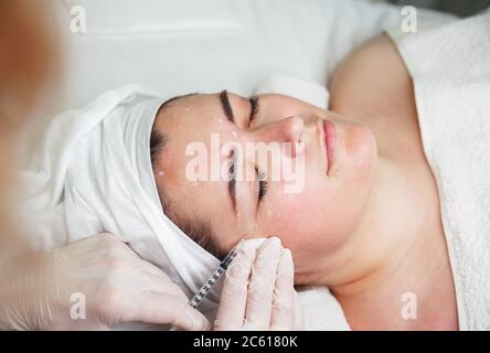 Le médecin trace un point pour les injections sur le visage du patient, le levage Banque D'Images