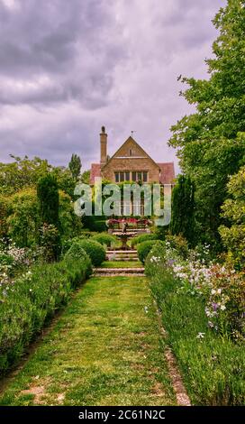 Chemin herbacé menant à une fontaine avec maison en arrière-plan au jardin de Kathy Brown à Stevington, Bedfordshire, Royaume-Uni Banque D'Images