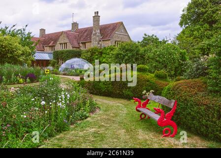 Un banc de style dragon inhabituel parmi les parterres de fleurs au jardin de Kathy Brown à Stevington, Bedfordshire, Royaume-Uni Banque D'Images