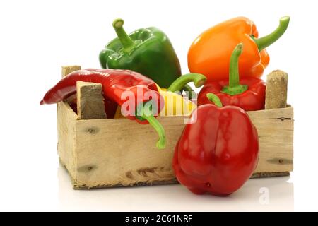 mélange coloré de paprika's(capsicum) dans une boîte en bois sur fond blanc Banque D'Images