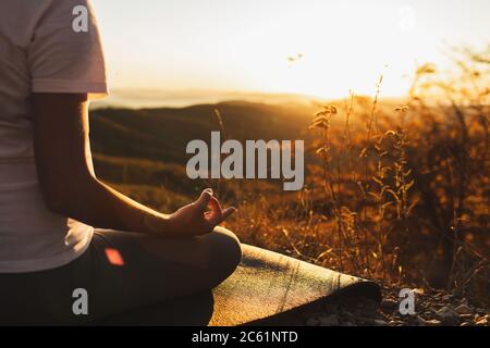 Femme main en position lotus gros plan. Méditation Zen. Mode de vie sain et concept de yoga. Arrière-plan de la lumière du soleil et de la vue sur la montagne. Emplacement vide. Banque D'Images