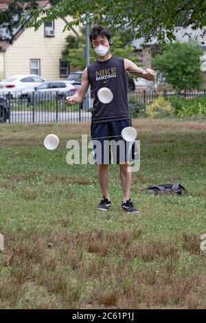 Un homme américain asiatique portant un masque chirurgical se produit sur un yoyo chinois appelé Diablo. À Kissena Park, Flushing, New York. Banque D'Images