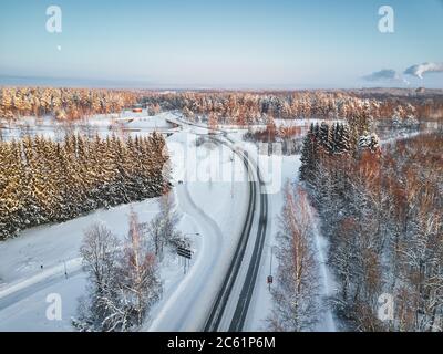 La route passe à la périphérie de la ville finlandaise de Joensuu, en hiver, beaucoup de neige, dans le ciel bleu de la lune Banque D'Images