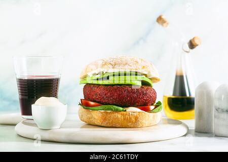 hamburger végétalien sans viande avec avocat, tomates et épinards sur la table et vin rouge dans un verre Banque D'Images