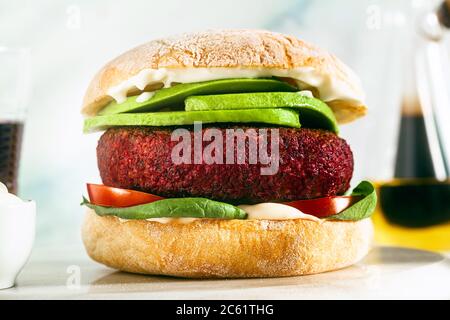 hamburger végétalien sans viande avec avocat, tomates et épinards sur la table et vin rouge dans un verre Banque D'Images