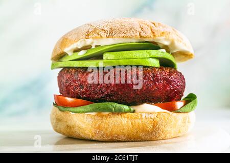 hamburger végétalien sans viande avec avocat, tomates et épinards sur la table et vin rouge dans un verre Banque D'Images