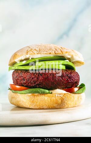 hamburger végétalien sans viande avec avocat, tomates et épinards sur la table et vin rouge dans un verre Banque D'Images