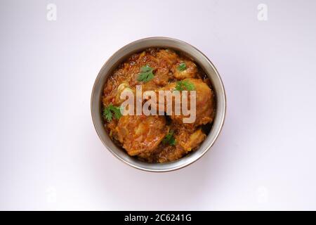 Vue de dessus du curry de poulet ou du masala, plat piquant de jambe de poulet rougeâtre garni de feuilles de coriandre, qui est traditionnellement arrangé Banque D'Images