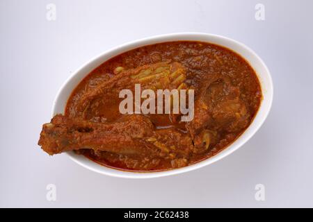 Curry de mouton ou curry d'agneau, plat épicé et délicieux disposé dans bol ovale blanc à texture ou arrière-plan blanc Banque D'Images