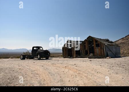 Un pick-up abandonné et une grange en ruine dans le désert du Nevada avec des montagnes. Ville fantôme de Rhyolite une ville minière abandonnée près de la Vallée de la mort Banque D'Images