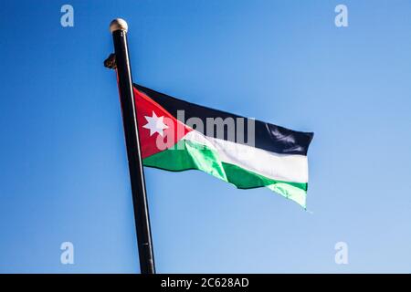 Un drapeau jordanien qui flotte dans la brise contre un ciel d'été. Banque D'Images