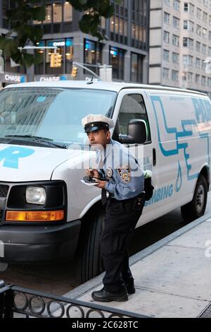 Le responsable de la circulation de NYPD a vu émettre un billet de stationnement pour une fourgonnette qui a dépassé sa période de temps dans un New York occupé. Banque D'Images