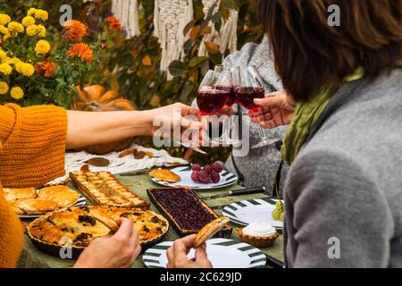 Déjeuner familial dans l'arrière-cour. Femmes-hommes boivent du vin et rient. Banque D'Images