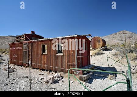 Une Union abandonnée caboose du pacifique entourée d'une clôture en treillis métallique dans le désert. Ville fantôme de rhyolite ancienne ville minière dans le Nevada près de la Vallée de la mort. Banque D'Images