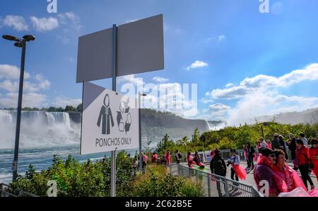 Vue panoramique sur les chutes du Niagara montrant des membres du public qui font la queue pour une excursion en bateau dans une brume intense. Banque D'Images