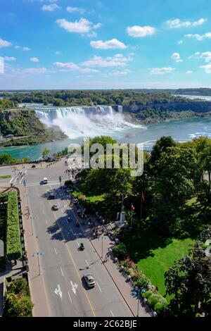 Vue panoramique sur les chutes du Niagara montrant des membres du public qui font la queue pour une excursion en bateau dans une brume intense. Banque D'Images