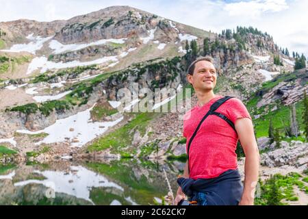 Albion Basin, Utah été avec un homme heureux debout regardant la vue par réflexion de l'eau sur le lac Cecret dans les montagnes de Wasatch avec des rochers, de la neige et de la frénésie Banque D'Images