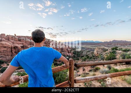 Grand angle d'homme regardant la vue du lever du soleil matin dans le parc national d'Arches, Utah, États-Unis au point de vue de Fiery Furnace à Overview Rail Banque D'Images