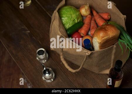 sac écologique en toile de jute naturelle avec supports de nourriture et de légumes sur une table en bois. Concept ECO. Banque D'Images