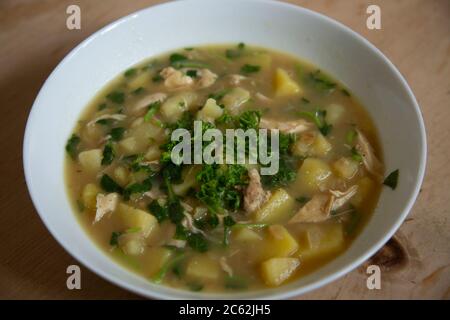 Soupe de poulet maison avec pommes de terre, persil, cresson dans un bol blanc Banque D'Images