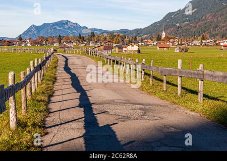 Un sentier de randonnée bordé de clôtures en bois mène vers le village d'Oberstdorf dans la région de l'Allgäu en Bavière, Allemagne. Banque D'Images