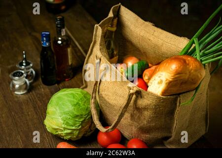 sac écologique en toile de jute naturelle avec supports de nourriture et de légumes sur une table en bois. Concept ECO. Banque D'Images