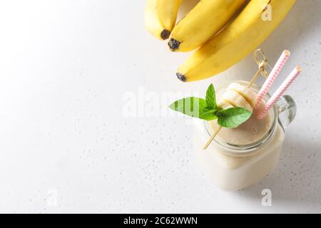 Milk-shake de banane sain dans un pot de maçon sur blanc. Banque D'Images