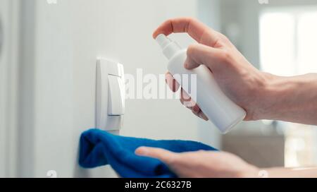 gros plan. un homme traitant un interrupteur mural avec un spray antibactérien. Banque D'Images