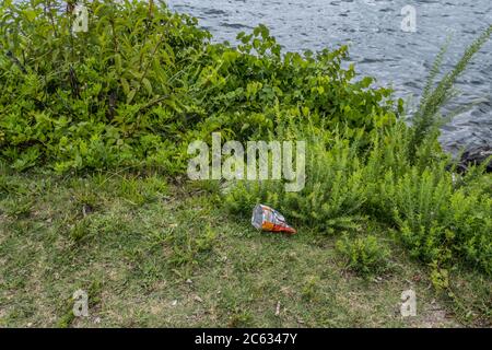 Des jetons ou un sac de collation déversés sur le sol du parc au bord du lac, par le rivage, polluent inlassablement l'environnement Banque D'Images