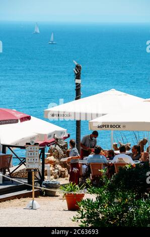 Les gens se détendent sur une terrasse de restaurant avec une vue fantastique sur l'océan à Casa da Guia à Cascais, Portugal pendant l'épidémie de coronavirus Covid-19 Banque D'Images